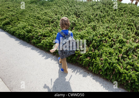 Boy walking by shrubs outdoors