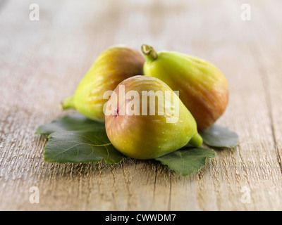three figs with leaves on rustic table Stock Photo