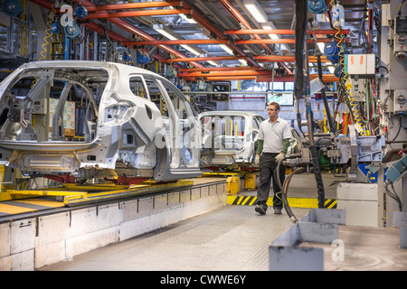 Workers with car bodies on production line in car factory