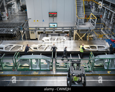 High angle view of workers handling car parts as they come out of press in car factory