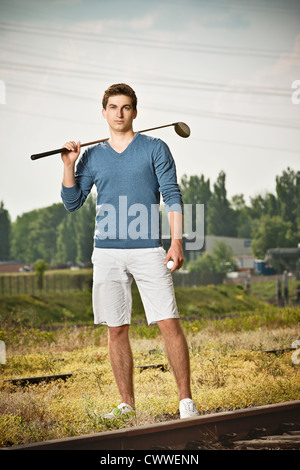 Man playing golf on train tracks Stock Photo