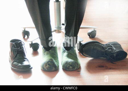 Businessman wearing slippers at desk Stock Photo