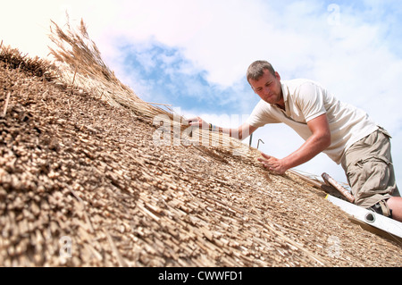 Man working on straw roof Stock Photo