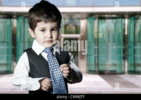 child dressed businessman smiling in front of building Stock Photo