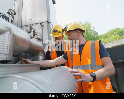Workers examining machinery on site Stock Photo