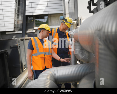 Workers examining machinery on site Stock Photo