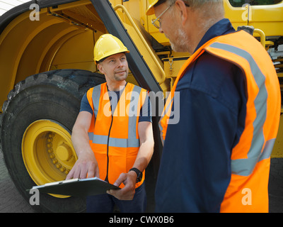 Workers reading clipboard on site Stock Photo
