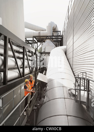 Workers examining machinery in factory Stock Photo