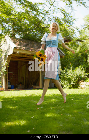 Woman carrying flowers in backyard Stock Photo