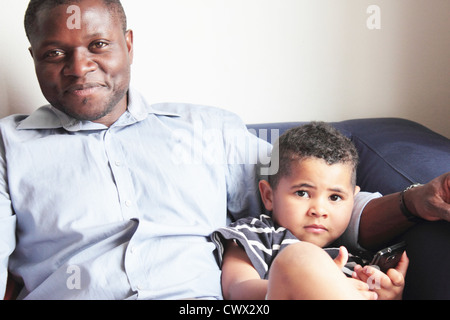 Father relaxing with son on sofa Stock Photo
