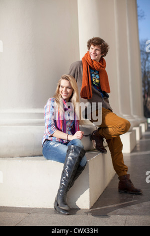 Couple sitting by pillars on building Stock Photo