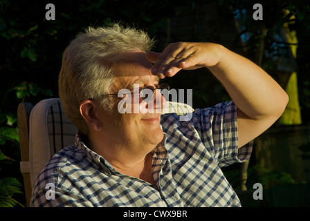 Man shading his eyes from the evening sun Stock Photo
