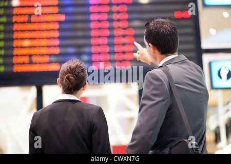 businessman and businesswoman checking flight information at airport Stock Photo