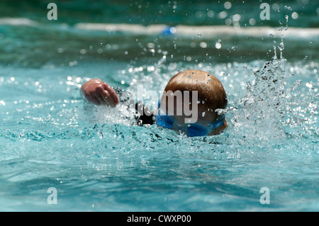 A young boy swimming in an outdoor pool Stock Photo