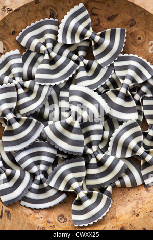 Farfalle Zebra pasta in a wooden bowl. Flavored coloured Pasta. Specialty pasta Stock Photo