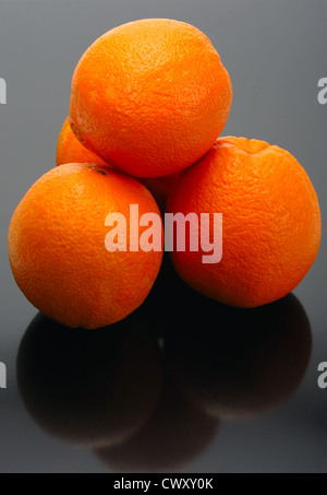Four oranges and their reflection on a black background