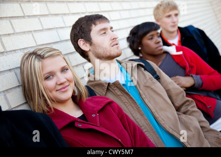 A group of multi-ethnic college students/friends leaning against a brick wall Stock Photo