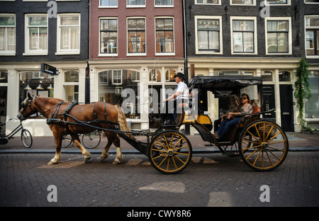 Horse-drawn carriage on cobblestone street, Amsterdam, Netherlands Stock Photo