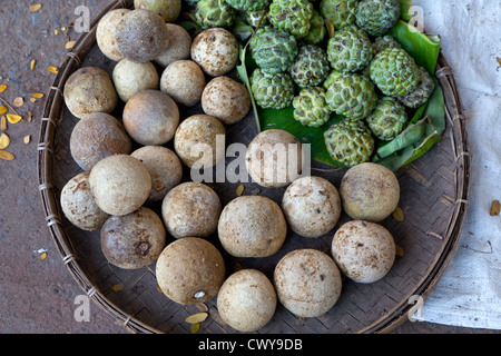 Myanmar, Burma, Mandalay. Wood-Apples (brown) and Custard Apples (green) for Sale in the Market. Stock Photo