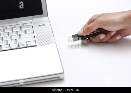 person inserting a USB thumb drive into a laptop Stock Photo