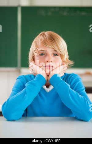 Schoolboy in classroom with hands on chin, portrait Stock Photo