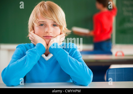Schoolboy in classroom resting his head in hands, portrait Stock Photo