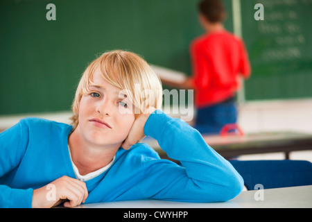 Schoolboy in classroom resting his head in hand, portrait Stock Photo