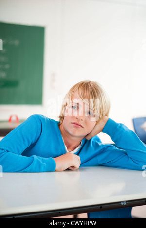 Schoolboy in classroom resting his head in hand, portrait Stock Photo