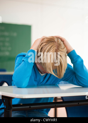 Exhausted schoolboy in classroom Stock Photo