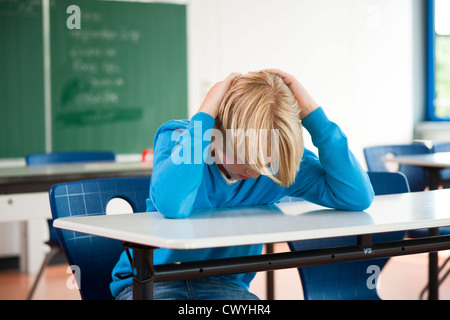 Exhausted schoolboy in classroom Stock Photo