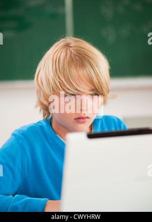 Schoolboy using laptop in classroom Stock Photo