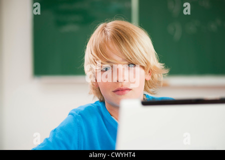 Portrait of schoolboy using laptop in classroom at school Stock Photo ...