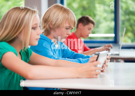 Schoolchildren using laptop and tablet pc in classroom Stock Photo