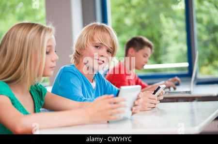 Schoolchildren using laptop and tablet pc in classroom Stock Photo