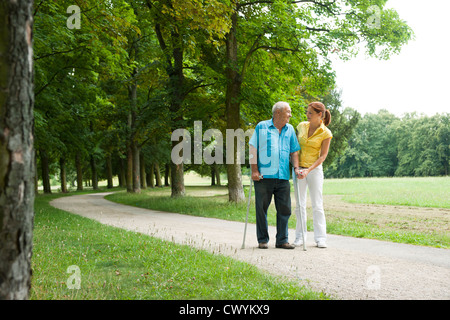 Woman walking with old man in park Stock Photo