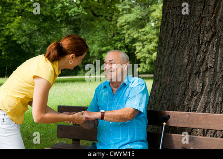 Woman with old man on park bench Stock Photo