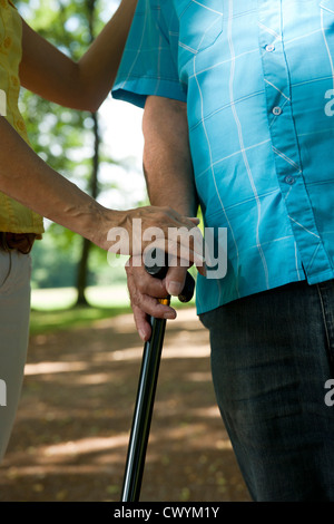 Woman assisting old man in park Stock Photo