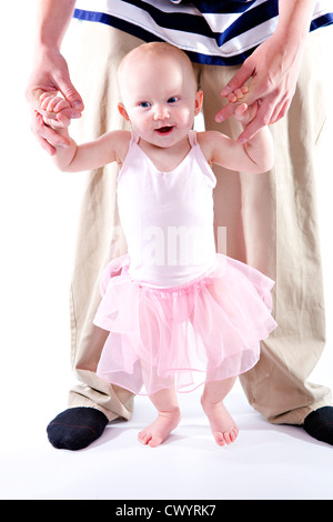 A man holds his daughters hands to help her stand Stock Photo