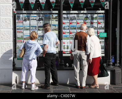 Two couples, one holding hands, outside estate agents office in Caernarfon Wales UK Stock Photo