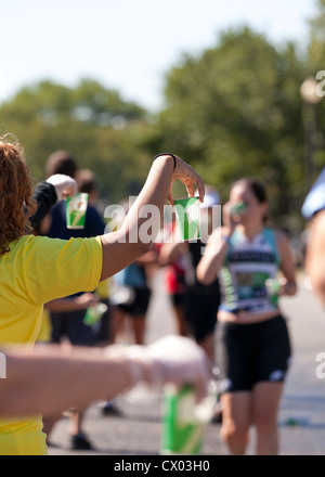 Marathon volunteer offering water to runners Stock Photo