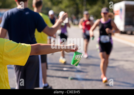 Marathon volunteer offering water to runners Stock Photo