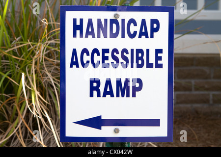 Sign in front of a building points to a handicapped accessible ramp for use by the disabled. Stock Photo