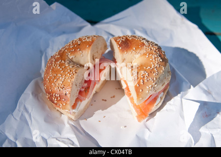 A sesame seed bagel with lox (smoked salmon), cream cheese, onion and tomato, sitting on a paper wrapper, from Spring Tree Bagels in Englewood, NJ. Stock Photo