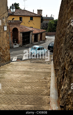 Looking down stairway to old light blue Fiat 500 parked in street, Guardistallo Tuscany Italy Stock Photo