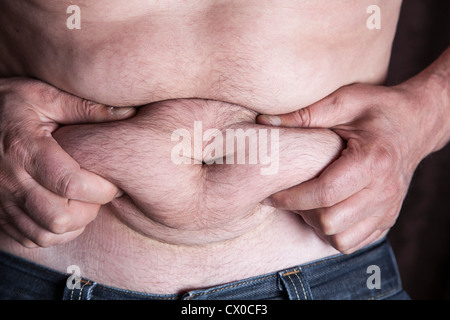 Middle aged man shows stomach fat Stock Photo