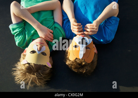 Two Boys Wearing Animal Masks lying on Back