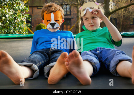 Two Boys Wearing Masks Lying on Trampoline