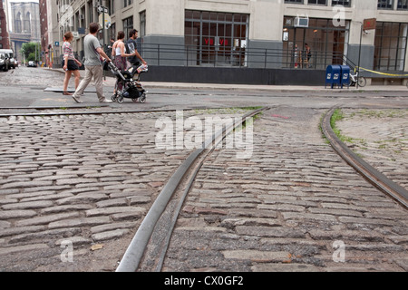 Tourists stroll along old cobblestone streets & trolley tracks in the DUMBO section of Brooklyn, New York past VII Photo Agency. Stock Photo