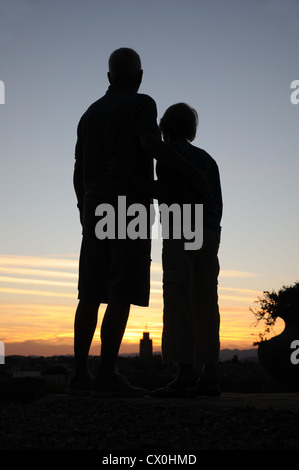 Couple embrace whilst sihouetted against dramatic sunset evening sky in southern France Stock Photo