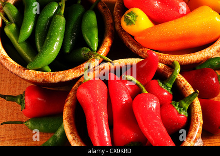 Closeup of an assortment of Sweet Peppers and Chilies in Bowls misted with water on a rustic wooden surface. Stock Photo